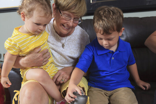 Grandmother with prosthetic leg allowing her grandchildren to play with her leg
