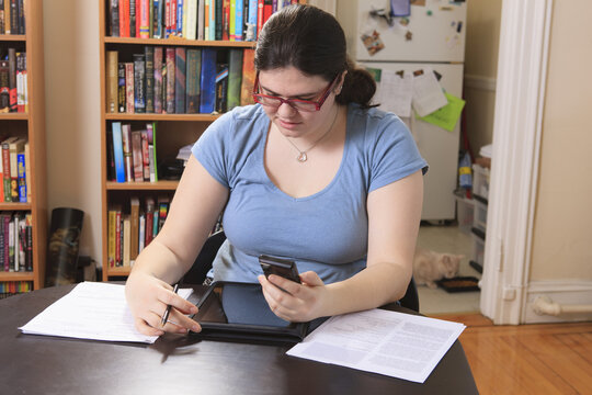 Woman with Asperger syndrome working with her smart phone and tablet from home office