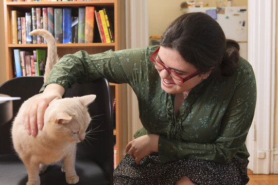 Woman with Asperger syndrome playing with her pet cat at home