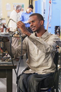 Student in wheelchair examining furnace ignitor in HVAC classroom