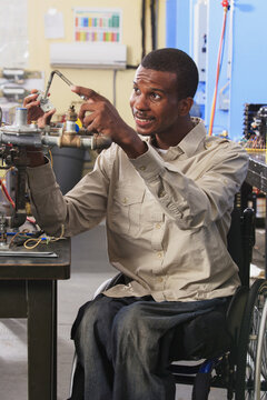 Student in wheelchair examining furnace ignitor in HVAC classroom
