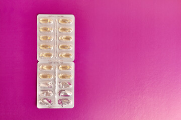 Vitamins in the form of capsules on a pink background. Treatment and prevention of diseases. Strengthening immunity.