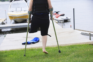 Woman with a prosthetic leg and crutches heading for waterskiing