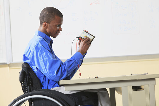 Engineering student in wheelchair from Spinal Meningitis placing components in prototyping breadboard