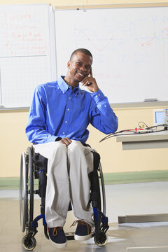 Engineering student sitting in a wheelchair with oscilloscope and electronic prototyping breadboard