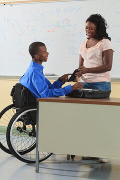 Two engineering students, one in wheelchair, looking at electronic tablet in a classroom
