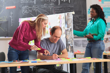 Engineering instructor with Aspergers reviewing technical notes with students in ideation lab