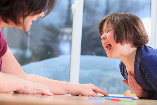 Little girl with Down Syndrome playing a learning game with her Mom