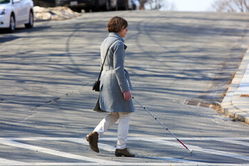 Young blind woman using her cane to cross the street