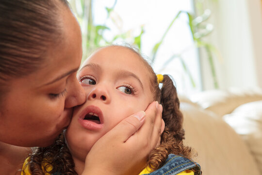 Mother kissing small daughter with Cerebral Palsy