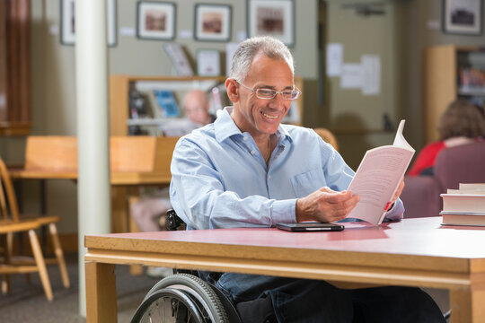 Man with Spinal Cord Injury in a library reading a book