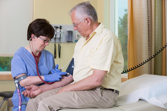 Nurse with Cerebral Palsy on cane checking a patient's blood pressure