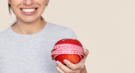 smiling woman with measure tape centimeter on shoulder or around red apple fruit isolated white...