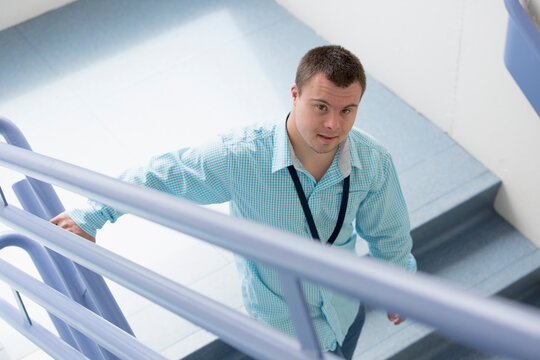 Young Man With Down Syndrome Working As A Hospital Aid On The Stairwell