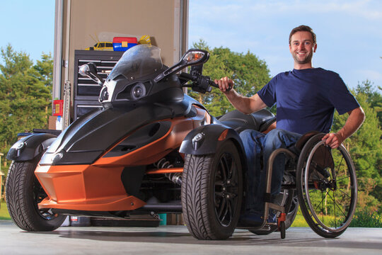 Man with spinal cord injury sitting in wheelchair beside his custom motorcycle