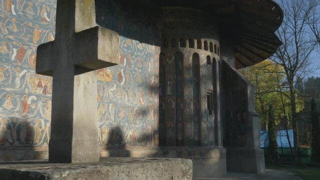 Painted exterior walls and stone cross of Voronet Monastery in Bukovina region