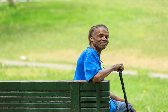 Man with Traumatic Brain Injury relaxing with his cane in a park