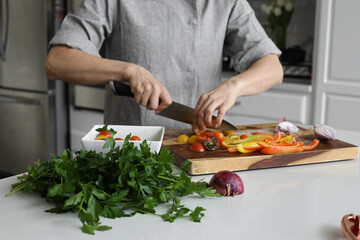 Cutting tomatoes in kitchen with parsley