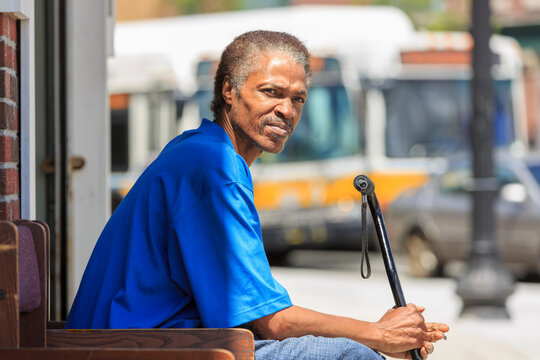 Man with Traumatic Brain Injury relaxing with his cane near the bus station