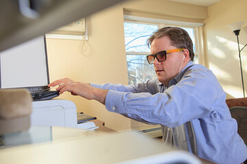 Man with congenital blindness scanning paperwork at his computer