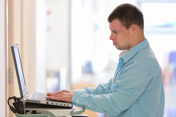 Man with Down Syndrome working in a hospital on computer patient records