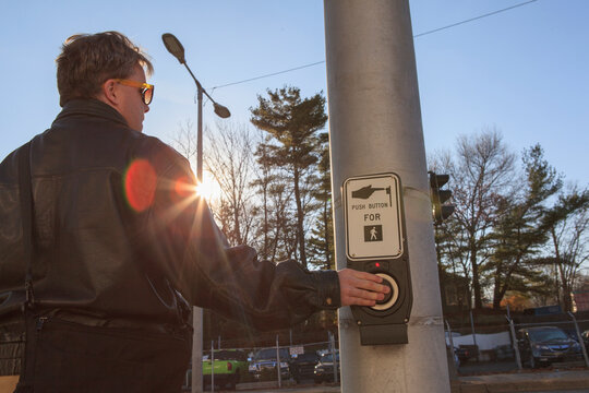 Man with congenital blindness pushing the street light button to stop cars so he can cross