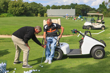Man with spinal cord injury in an adaptive cart at golf putting green with an instructor