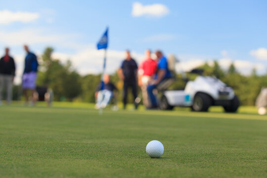 People with disabilities and an adaptive golf cart at a putting green