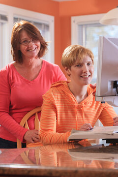 Young woman with visual impairment and her mother working at her desktop magnifier