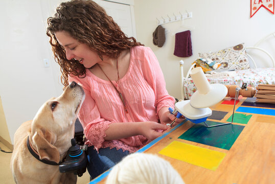 Woman with Muscular Dystrophy working with her knitting and talking to her service dog