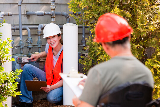 Engineer in wheelchair with Spinal Cord Injury discussing energy efficiency data with female engineer in front of gas meter