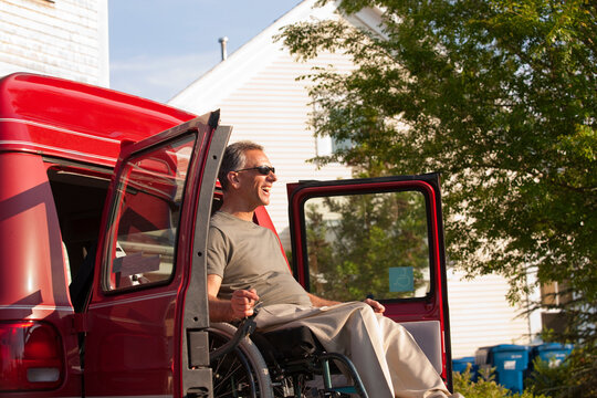 Man in wheelchair with Spinal Cord Injury being lowered from accessible van