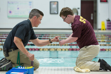 Young man with Down Syndrome working at college testing PH in swimming pool with supervisor