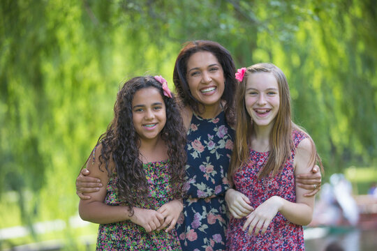 Portrait of happy Hispanic mother and two teen daughters with braces in park