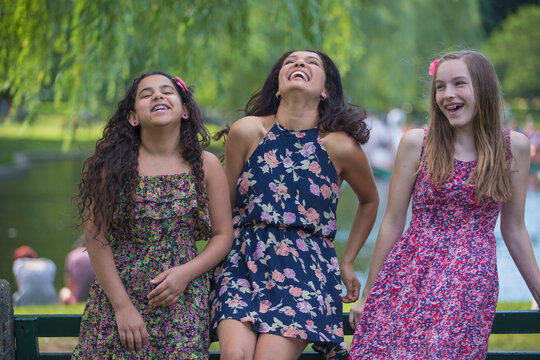 Happy Hispanic woman with her teen daughters with braces laughing in a park