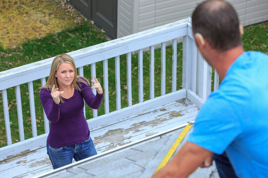 Homeowner signing 'Roof' in American Sign Language to a roofer with hearing impairment