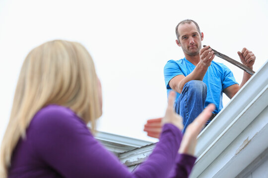 Homeowner signing, Old needs replaced, in American Sign Language to a roofer with hearing impairment on roof