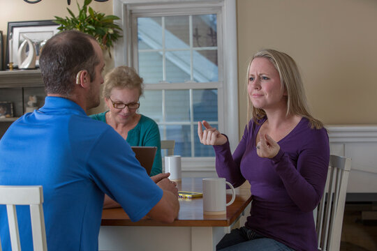 Three people having a meeting and two communicating in ASL about 'What are the plans' at home