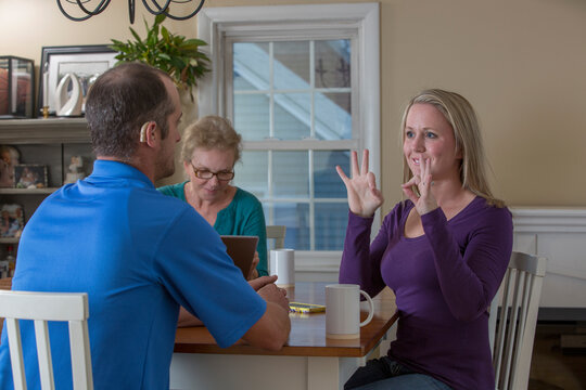 Three people having a meeting and two communicating in ASL about 'Perfect' at home