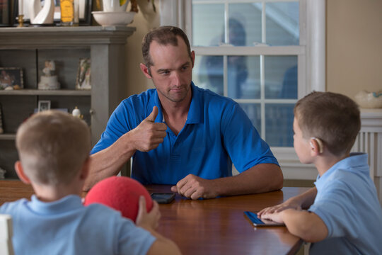Father communicating to sons in American Sign Language about 'Cool and good job' at home