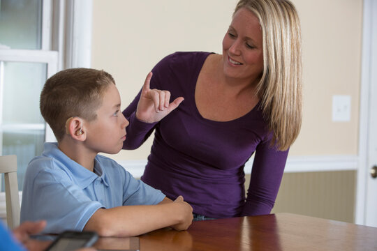 Mother communicating with son in American Sign Language 'Oh, OK' at home