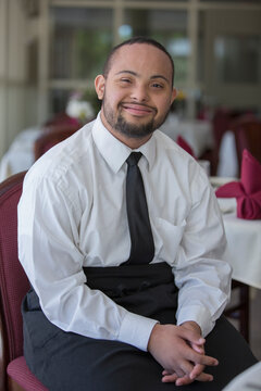 Portrait of happy African American man with Down Syndrome as a waiter in restaurant