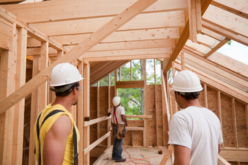 Hispanic carpenters studying their work on framing at a house under construction