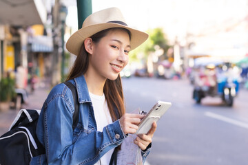 Traveler travel on vacation weekend, holiday in summer, smile attractive asian young traveling woman, girl backpacker using smartphone, walking in Khao San Road, Street outdoor market city in Bangkok.