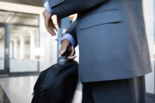 Close up of a young business man holding a briefcase.