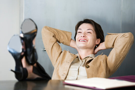 Business woman relaxing in office with her legs on the desk.