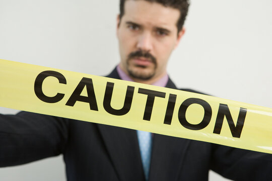 Portrait of a businessman holding a Caution tape