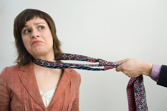 Close-up of a person's hand pulling a businesswoman with her tie