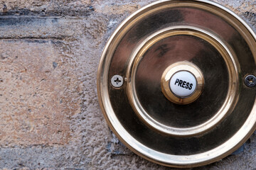 Vintage doorbell on rough wall brick.