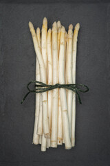 White asparagus tied in a bundle on a slate cutting board